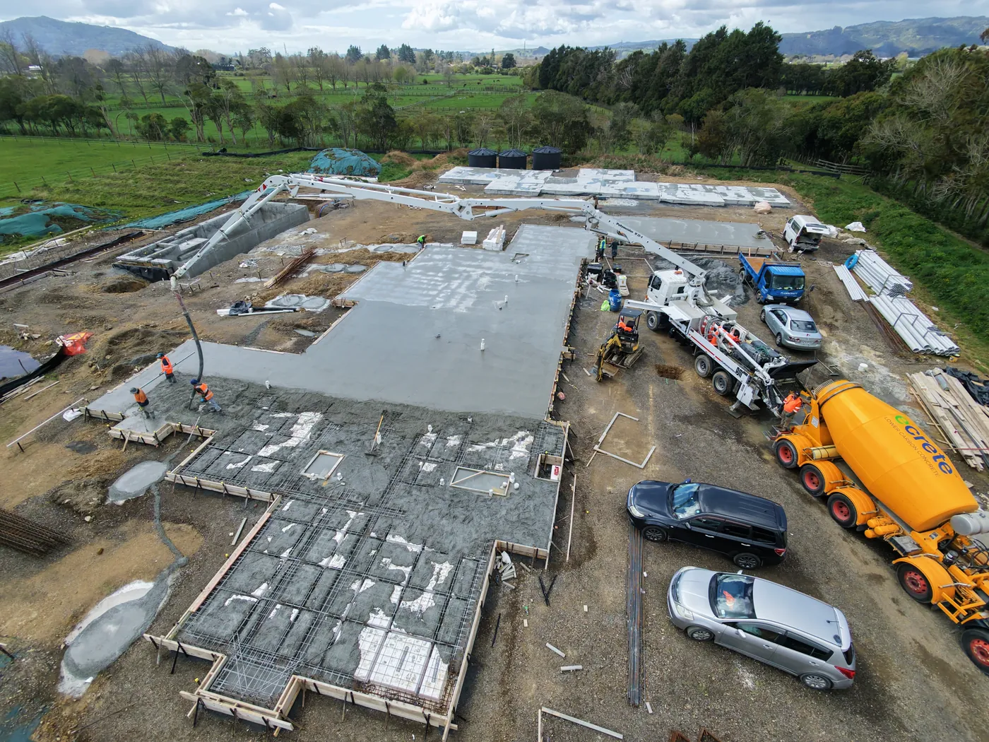 Aerial view of a poured concrete slab and reinforced footing bays with a concrete truck on a GTD Construction site